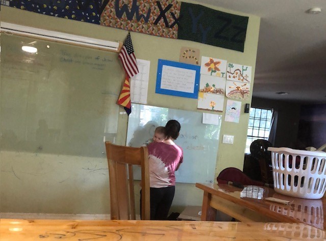 woman holding a baby and writing on a large white board