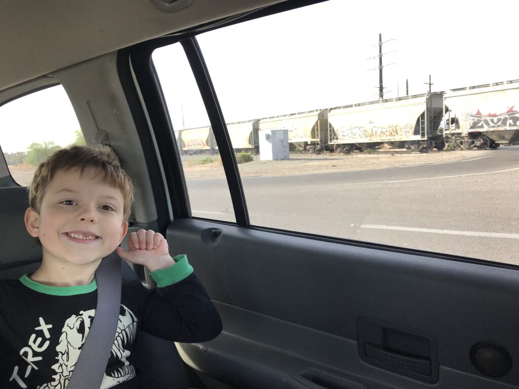 smiling boy in a car, a train out the window