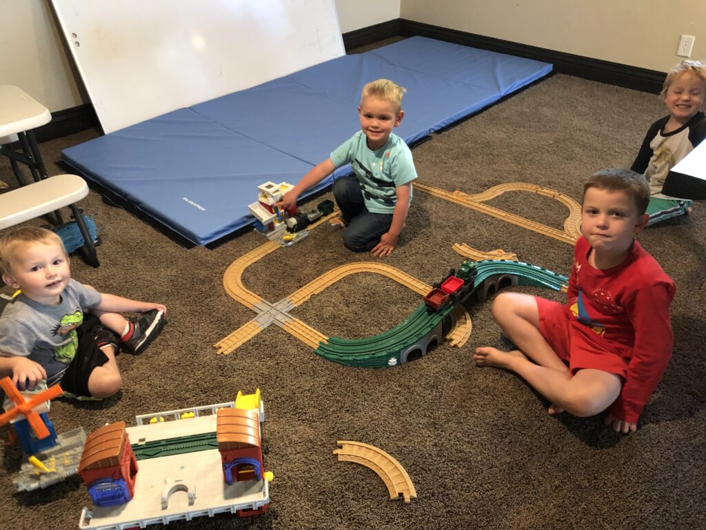 4 boys playing with a trainset on the floor