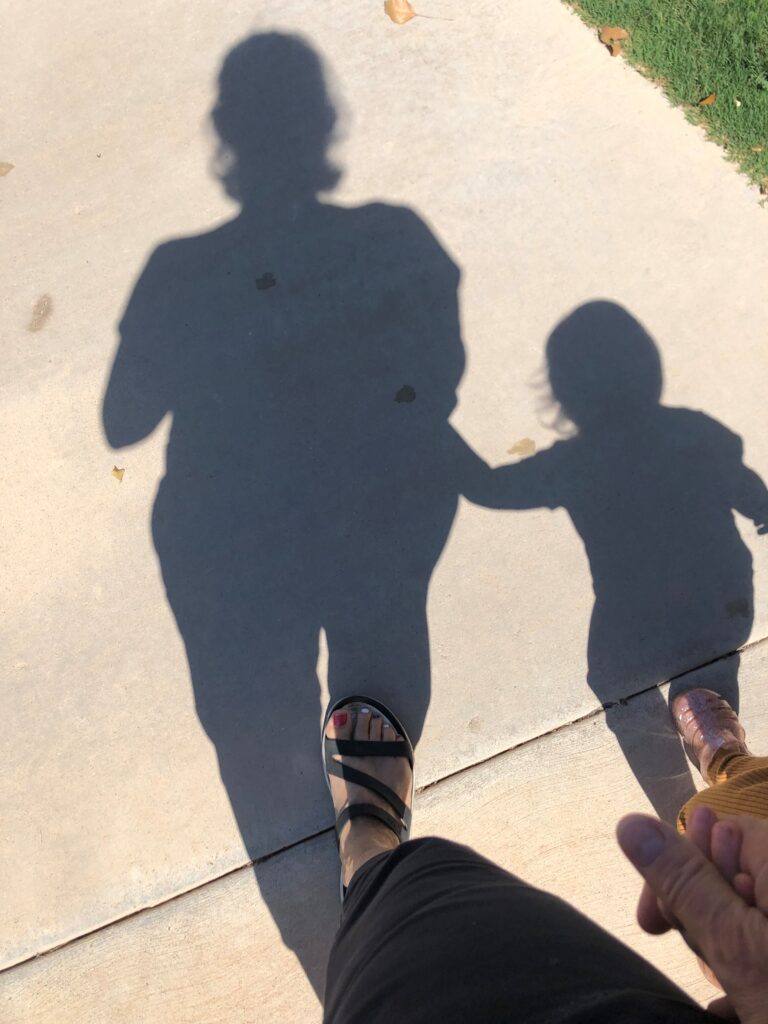 shadows of a woman and child on the sidewalk