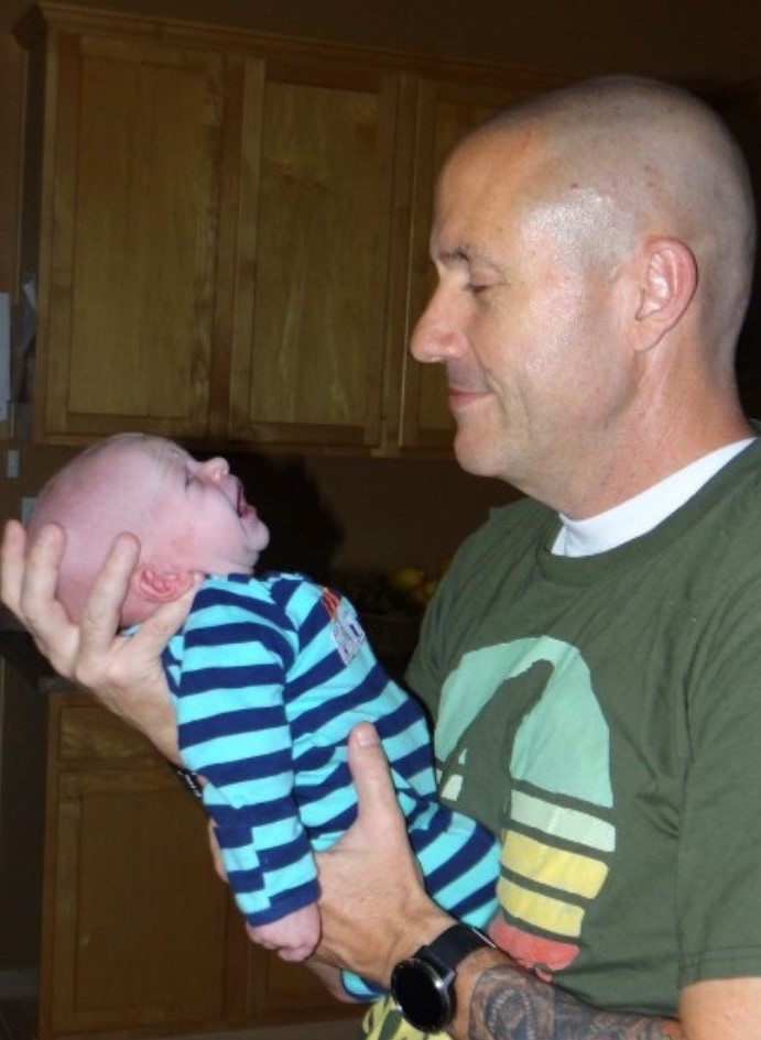 man smiling at a baby in his hands