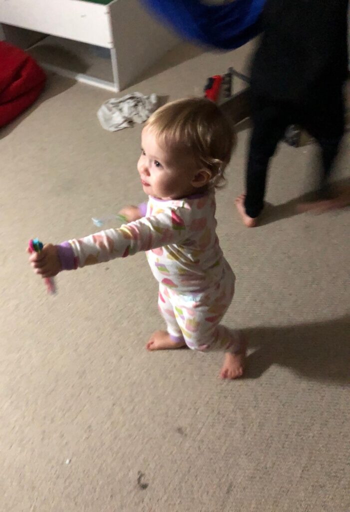 a toddler girl holding out a toothbrush