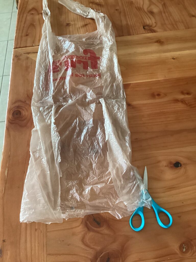 a plastic bag with both handles cut at one end and cut down the sides so it lays open