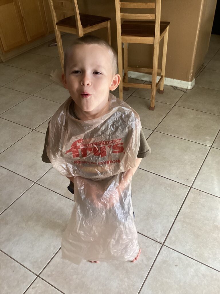 a little boy wearing a plastic bag apron