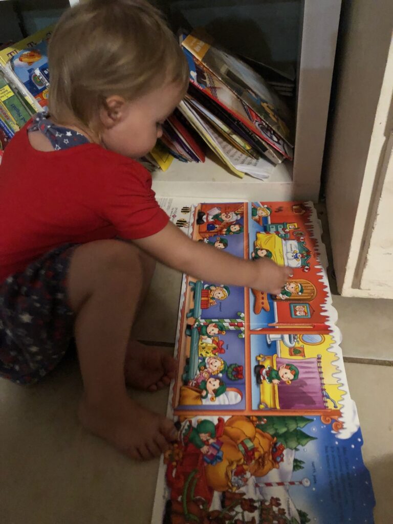 a toddler girl opening the flaps of a board book