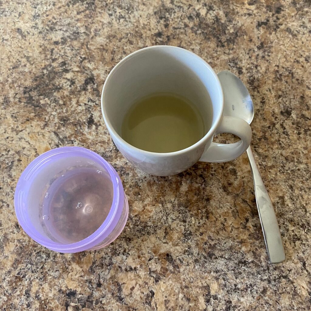 a mug and baby cup with amber colored liquid and a spoon