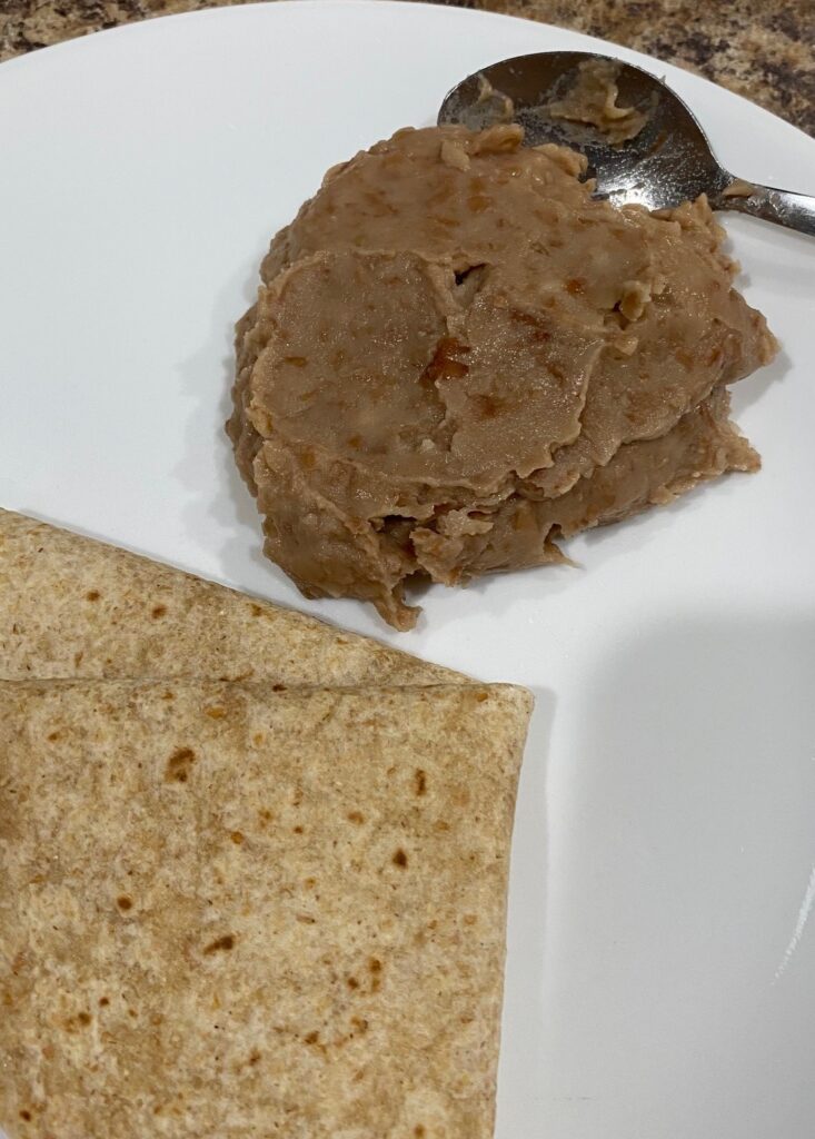 a plate with a whole wheat tortilla and home made refried beans