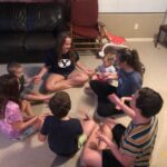 7 kids sitting together on the floor playing a hand game