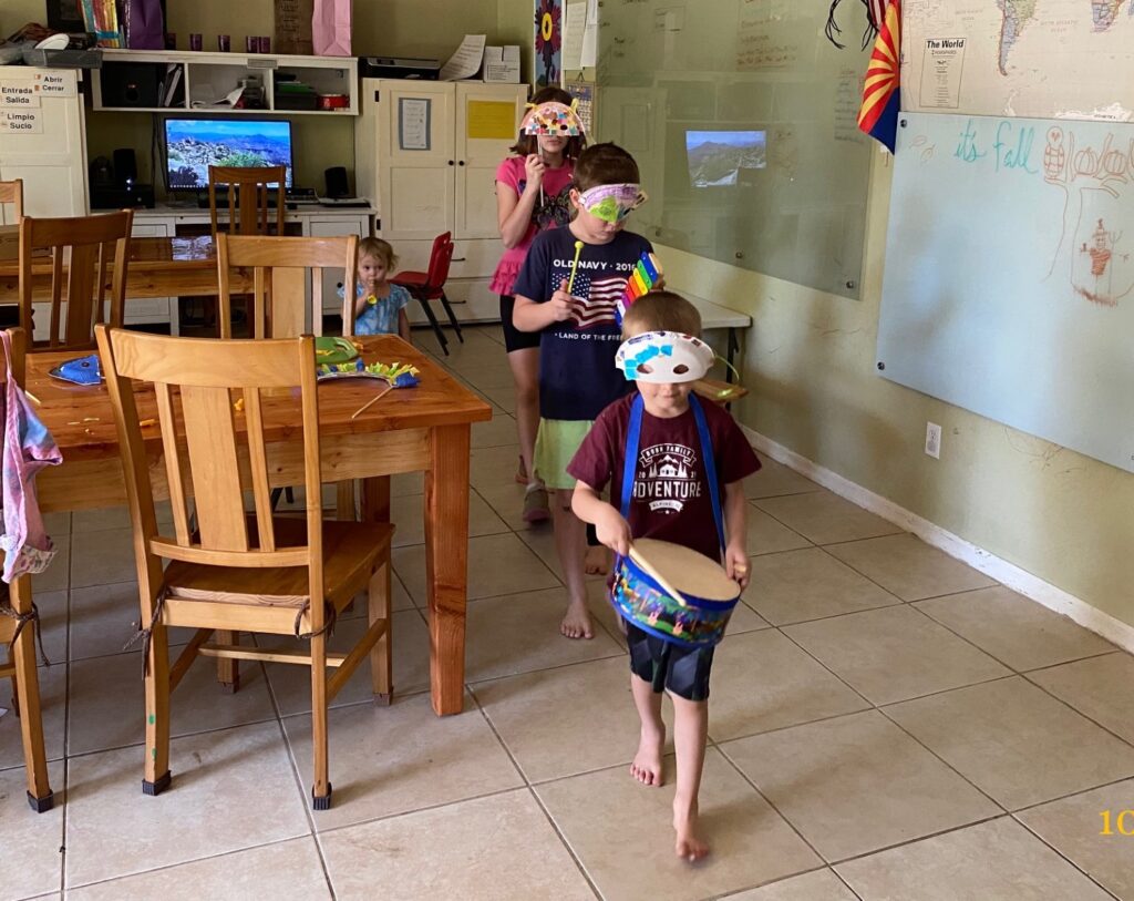 children parading around a table with masks and instruments for carnaval