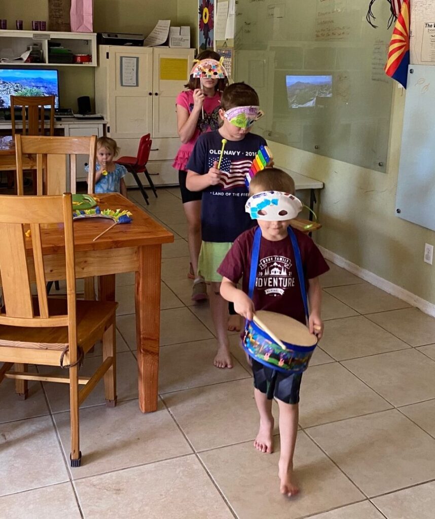 children parading around a table with masks and instruments for carnaval