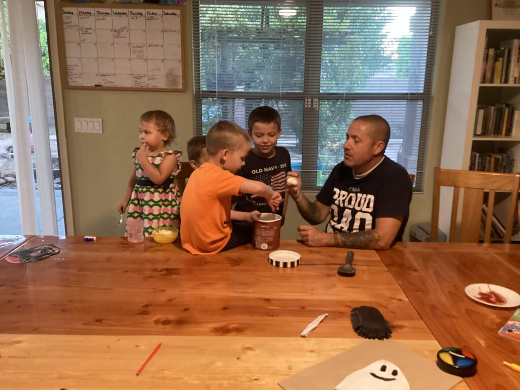 A dad and 4 kids sharing ice cream from a carton