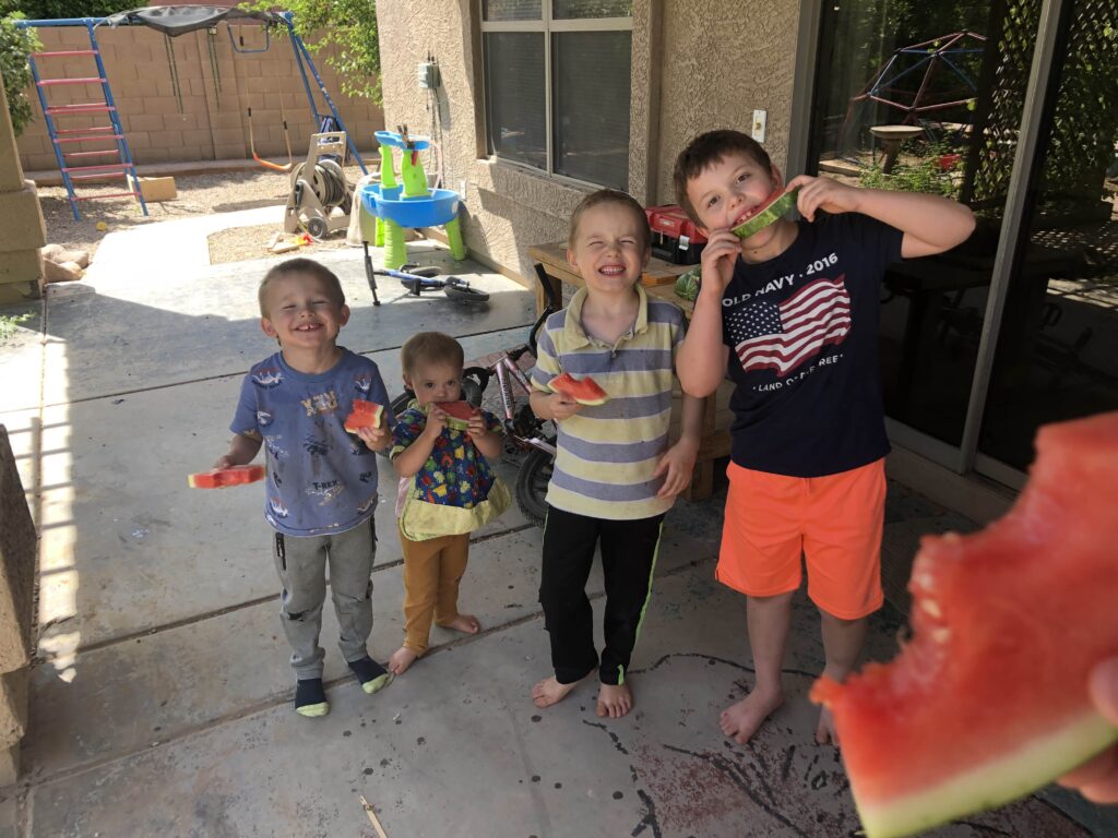 four little kids enjoying watermelon