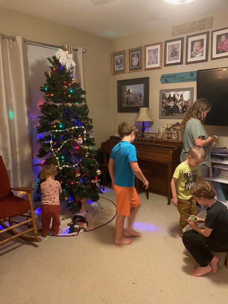 children putting up decorations around a Christmas tree