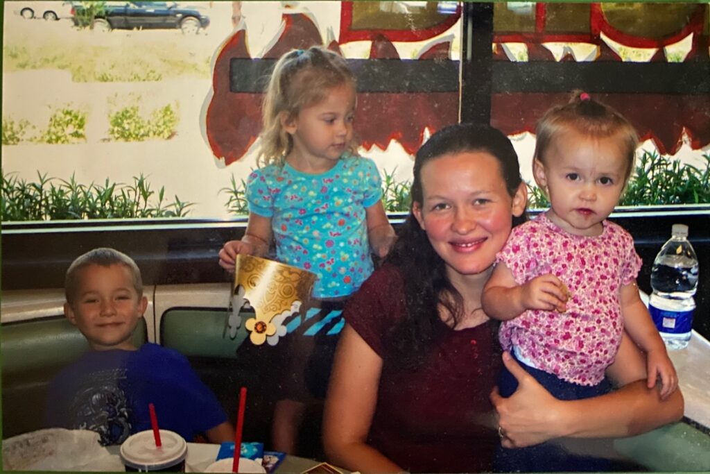 a woman in a restaurant booth with 3 little kids