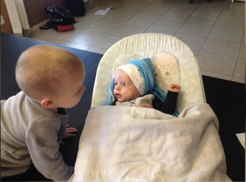 A baby and toddler looking at each other