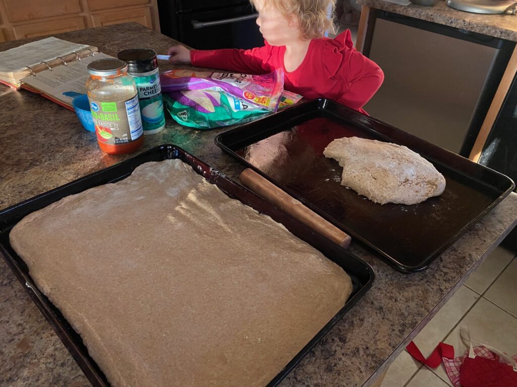 cookie sheets with dough and pizza ingredients