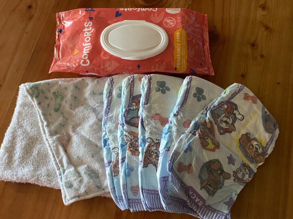 some diapers, a spit rag, and a package of baby wipes