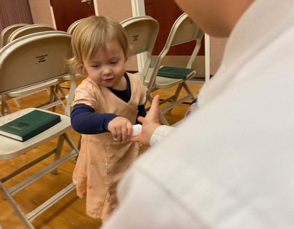 a little girl in a dress putting lotion on someone's hand