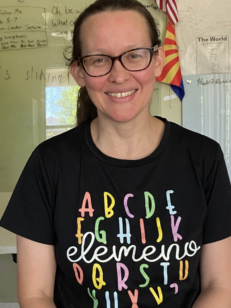 a smiling woman with glasses and her hair pulled back