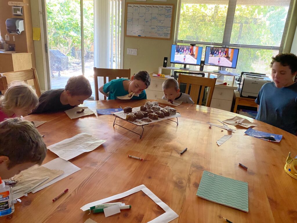 children at a table eating a lamington treat without their hands