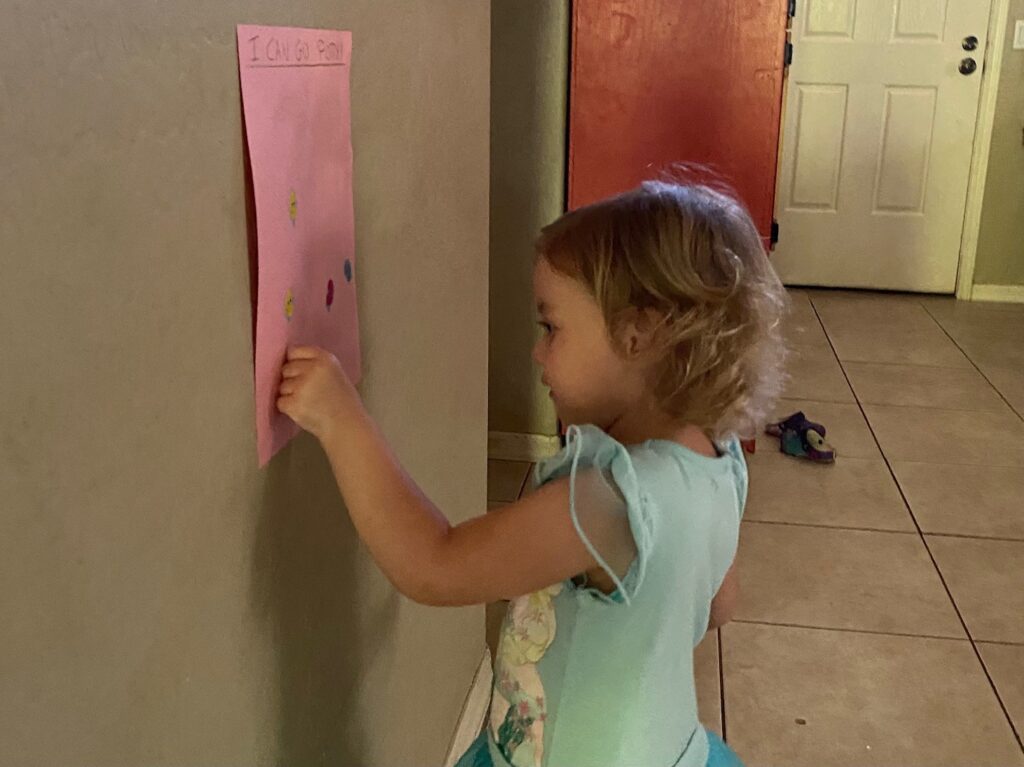 a little girl putting a sticker on a potty chart