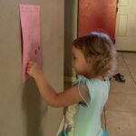 a little girl putting a sticker on a potty chart