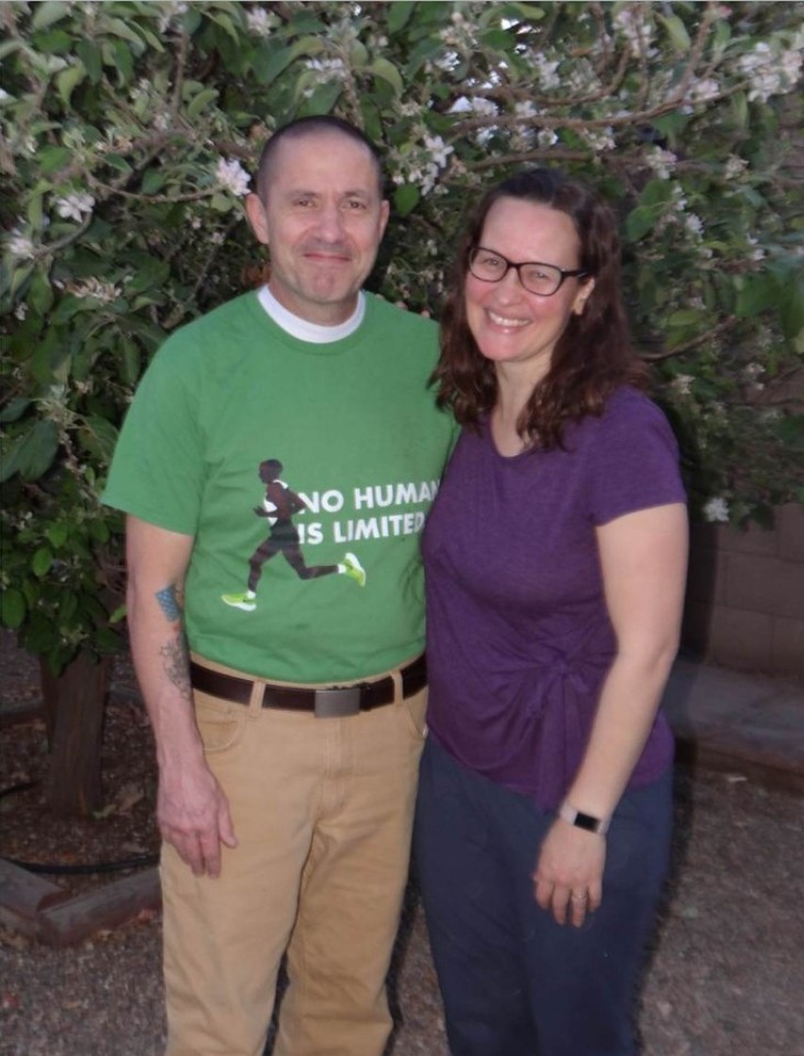 A man and woman standing in front of an apple tree