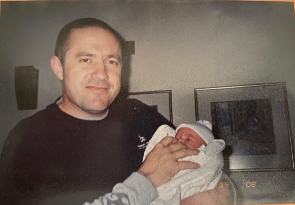 a smiling dad cradling his newborn