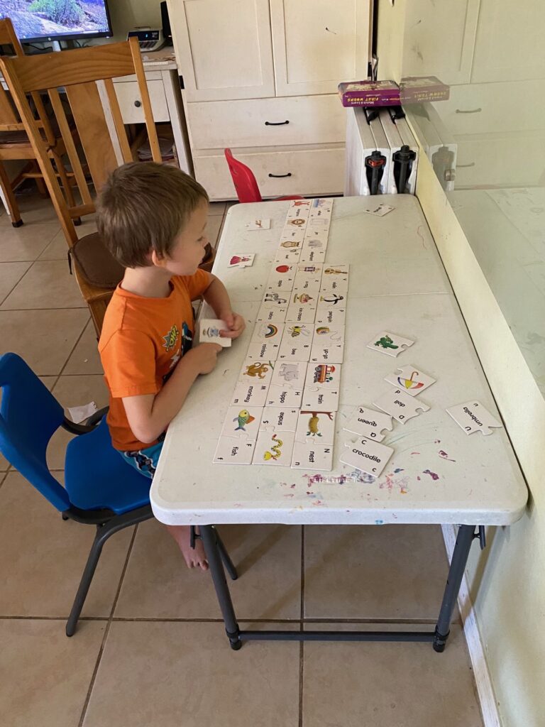 A boy at a small table doing phonics puzzles