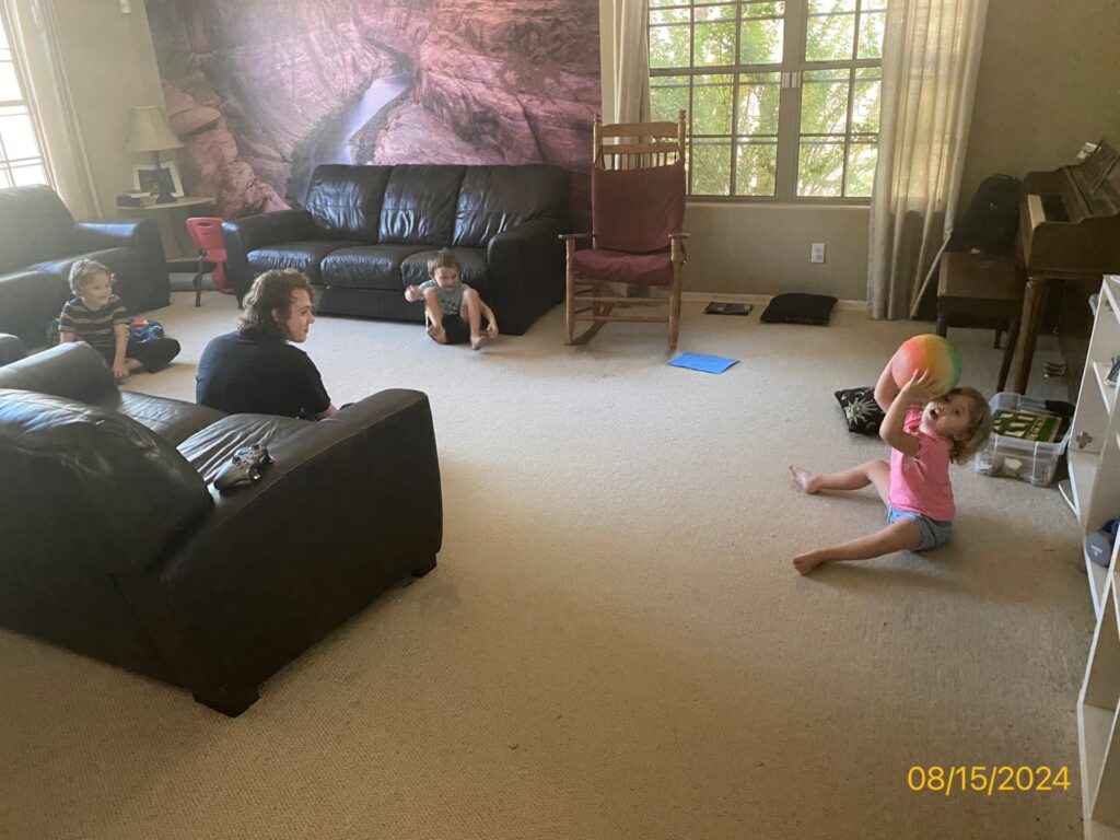 kids of different ages sitting together with a ball