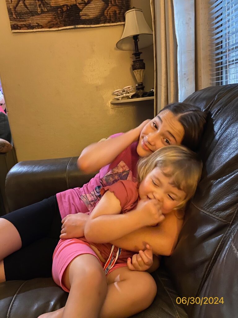 Sisters snuggling on a couch