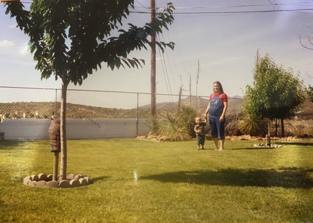 A pregnant mom and a little boy on grass