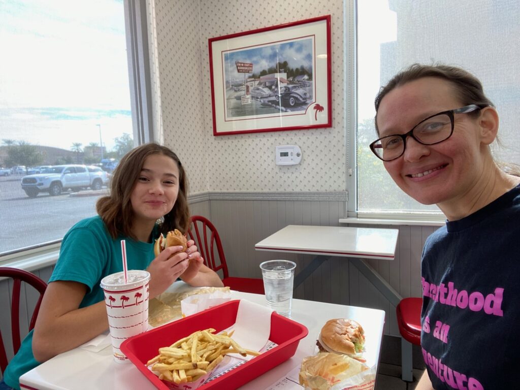 A mom and preteen eating a burger and fries