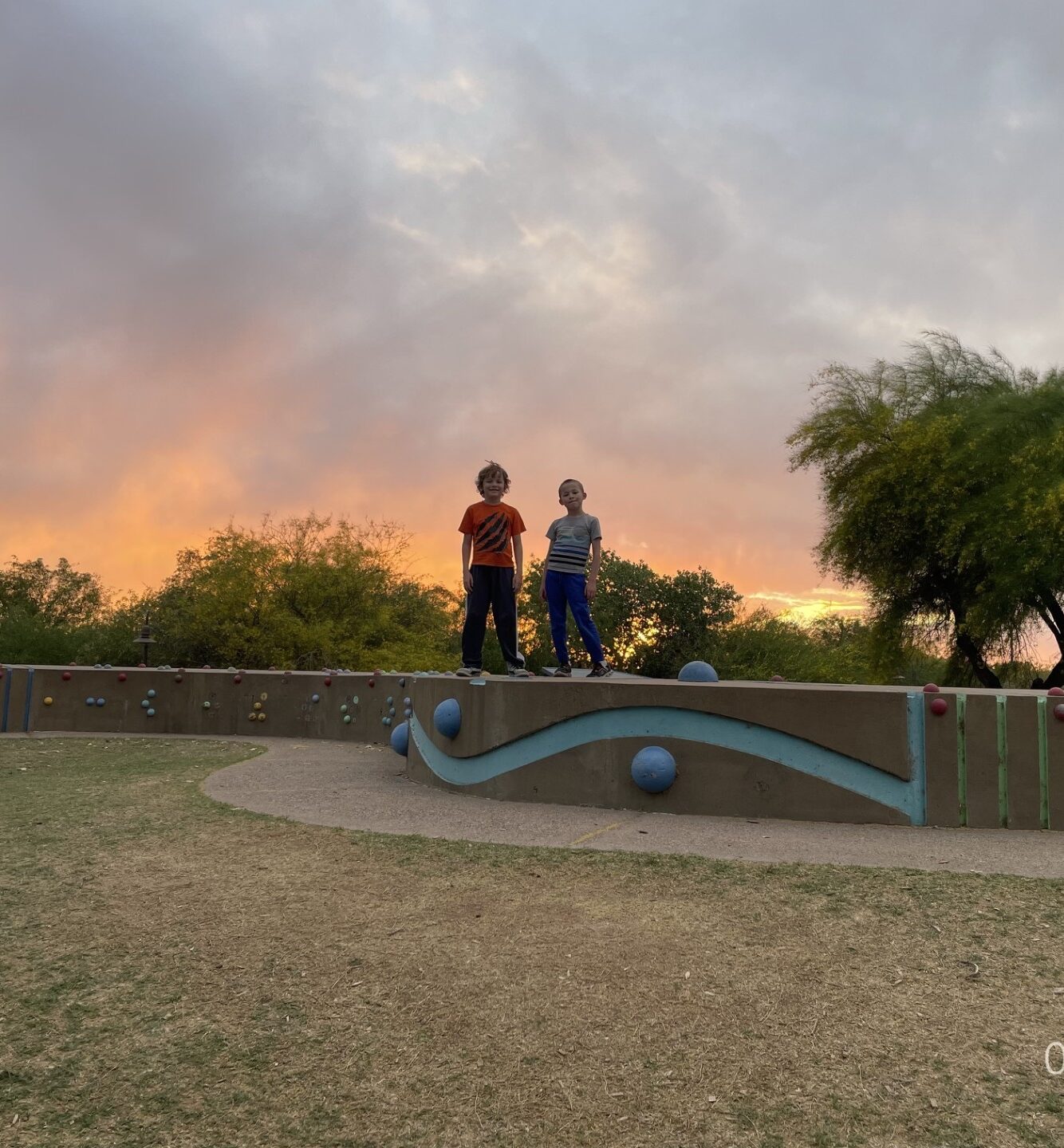 boys on a park walking wall with a stormy sunset in the background